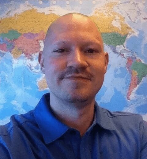 Smiling bald man posing before world map