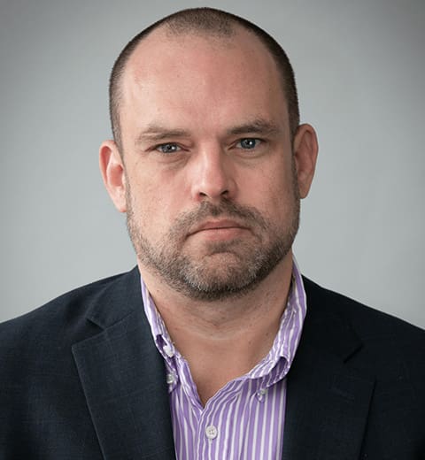 Man in striped shirt and dark blazer.