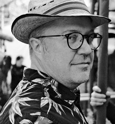 Man wearing hat and glasses, looking back.