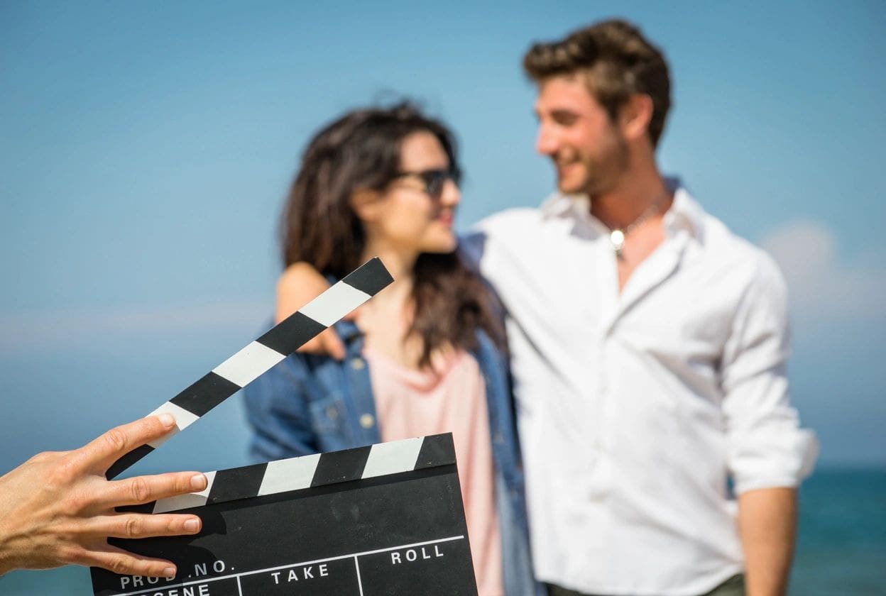 Couple posing on beach with film clapperboard.