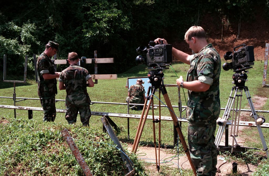 Military personnel operating cameras outdoors.
