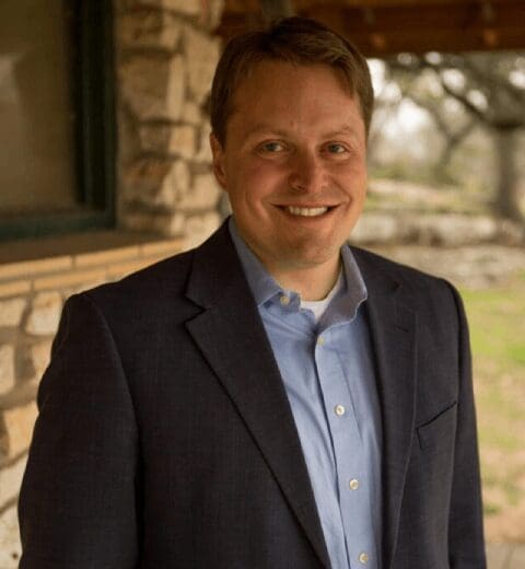 Smiling man in blue shirt and blazer.