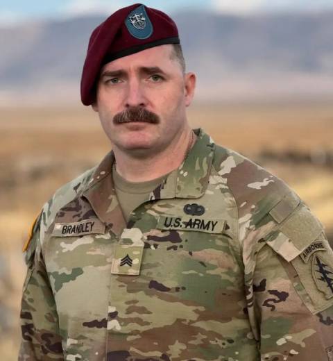 U.S. Army soldier in camo uniform outdoors.