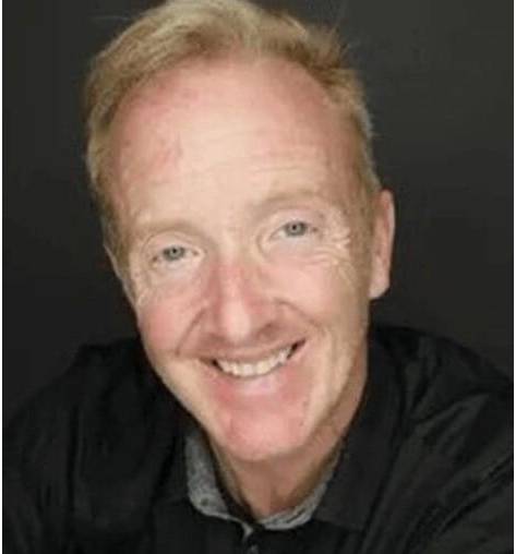 Smiling man with short, light hair.