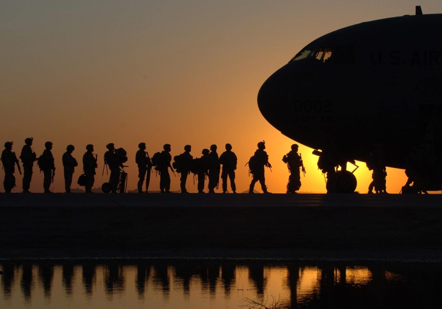 Soldiers boarding military transport at sunset